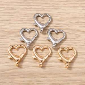 Vista macro di fermagli a moschettone a forma di cuore in oro e argento su legno