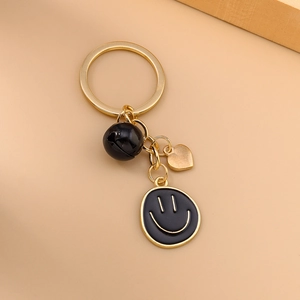 Porte-clés émoticône doré à la mode avec breloque cœur et clochette noire sur fond beige