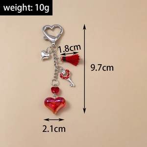 Détail du porte-clés cœur avec pompon et dimensions montrant 9,7 cm de longueur totale
