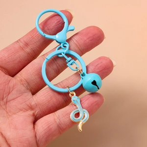 Cute sky blue zodiac snake keychain with golden bell and ring shown in hand