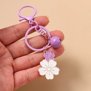 Detail of purple cherry blossom keychain with white enamel petals and matching bell charm