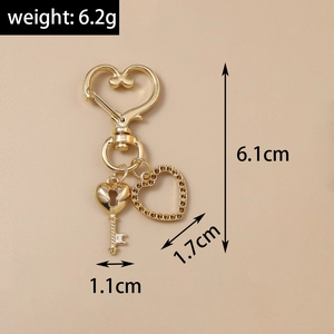 Détail d'un porte-clés doré en forme de cœur avec pendentif en cristal et breloque clé rétro