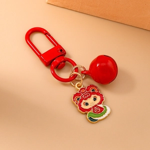 Detail of red cartoon lion keychain with D-ring buckle and bell on warm beige surface