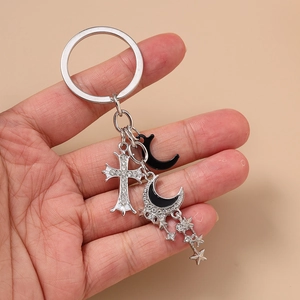 Porte-clés avec breloques étoile et lune et pendentif croix sur un fond marron uni
