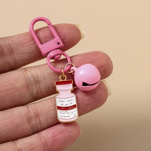 Close-up of a pink enamel medicine bottle pendant keychain with a bell and lobster clasp