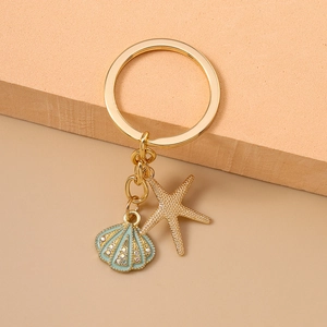 Chic gold metal keychain with blue shell and starfish charms on soft neutral background