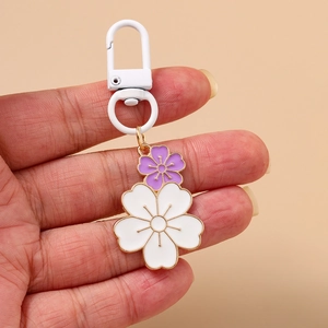 Detailed close-up of a double cherry blossom keychain with purple and white flower charms