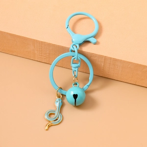 Detail of light blue metal snake keychain with bell and spring clasp on a warm background