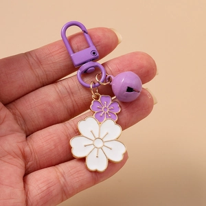 Fashionable cherry blossom keychain featuring purple and white enamel flowers and a bell