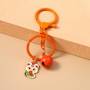 Close-up of a cartoon sheep keychain with a red bell and orange lobster clasp on a beige base