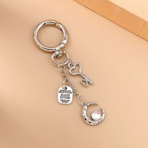 Detailed shot of silver keychain with crystal heart key, moon pendant and engraved metal tag