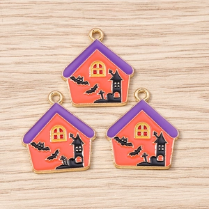 Macro detail of three enamel Halloween castle charms with bats on a wooden surface
