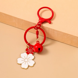 Detail of red cherry blossom keychain with enamel flower pendants and metal bell charm