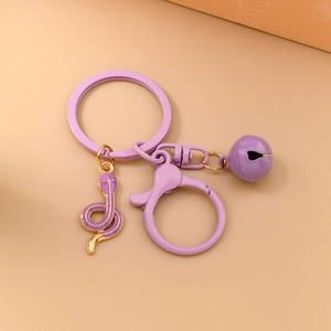 Detailed view of a purple zodiac snake keychain with golden edges and a small bell