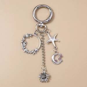 Détail du porte-clés en alliage avec breloques étoile de mer, lune rose et marguerite