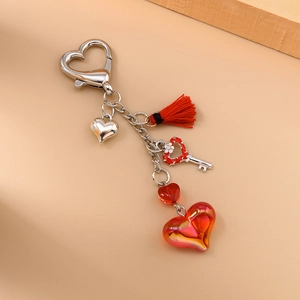 Détail d'un porte-clés cœur rouge avec gland, fermoir homard et pendentif à motif floral