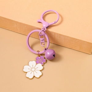 Detail of purple cherry blossom keychain with enamel flower charms and a small bell