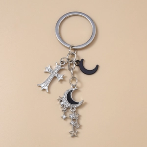 Gros plan détaillé sur un porte-clés croix argentée, lune noire et pampille étoilée