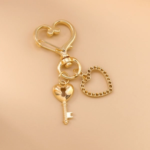 Gros plan d'un porte-clés cœur doré avec pendentif clé et détail de cœur en strass