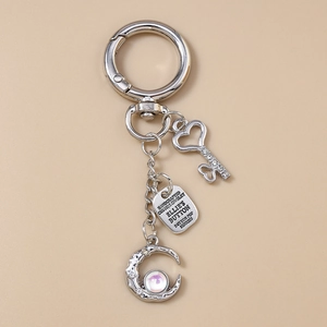 Detailed view of silver keychain with crystal heart key, moon pendant and metal tag charms