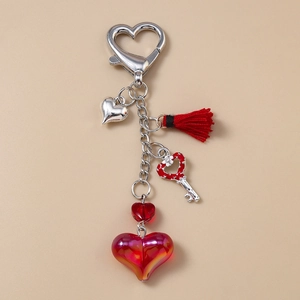 Détail du porte-clés cœur rouge avec pompon, breloque clé fleurie et boucle en argent