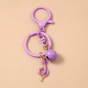 Close-up of a purple snake keychain with a round bell and gold-edged enamel charm
