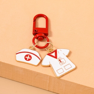 Detail of medical nurse hat and uniform enamel pendants on a red metal keychain