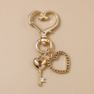 Détail du porte-clés cœur doré avec pendentif en strass sur fond cuir texturé