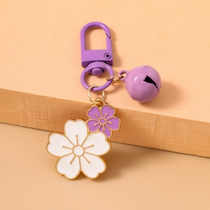 Detail of purple and white enamel cherry blossom charms with gold trim and a small bell