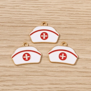 Détail de trois breloques en forme de bonnet d'infirmière avec croix rouge sur bois