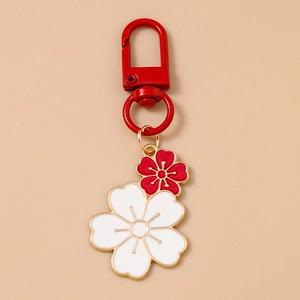 Detail of red and white cherry blossom enamel keychains with golden metallic finish and D-ring