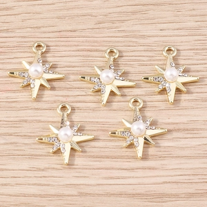 Goldene achtstrahlige Stern-Anhänger mit weißen Perlen und Strass auf Holzuntergrund