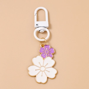 Detail of floral keychain with white and purple cherry blossoms and golden metal edges
