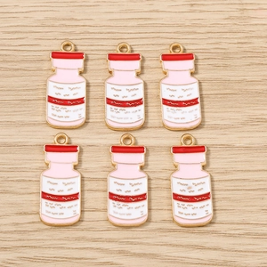 Vue macro de six breloques roses de flacons médicaux avec bords dorés pour bijoux DIY