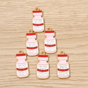 Détails macro des pendentifs flacons médicaux en émail rose pour la création de bijoux