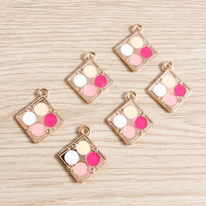 Detail shot of colorful alloy eyeshadow palette charms on a wooden surface for DIY jewelry