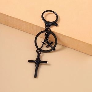 Makro-Detail von mattem schwarzen Kreuz-Schlüsselanhänger mit Karabiner auf Holz