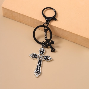 Detail eines gotischen Kreuz-Schlüsselanhängers mit schwarzen Anhängern und Federclip