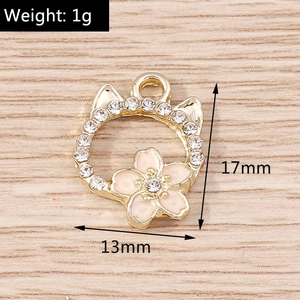 Macro detail of cat-shaped gold pendant with white rhinestones and pink enamel flower