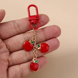 Minimalist red apple keychain with gold chain links and triple fruit pendants