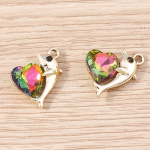 Dettaglio macro di ciondoli cuore delfino con gemme colorate su superficie in legno