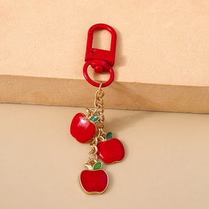 Detail of red apple pendants keychain with gold chain and lobster clasp on stone base