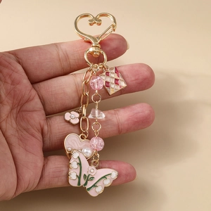 Pink butterfly and heart pendant keychain with beads and floral details on golden ring