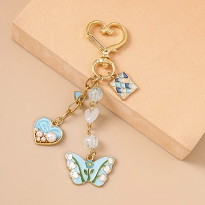 Detail of blue enamel butterfly and pearl heart pendants on a gold keychain