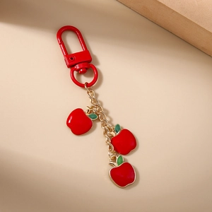 Detail of red apple keychain featuring three enamel pendants and gold lobster clasp