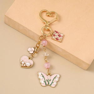 Pink heart and butterfly keychain with gold plating and enamel details on a display stand