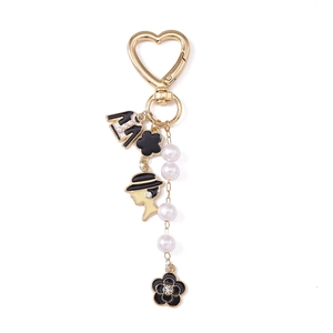 Golden heart-shaped keychain with black flower, handbag, pearl beads and female silhouette