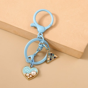 Detail of light blue heart keychain with inlaid pearls and mosaic triangle charm