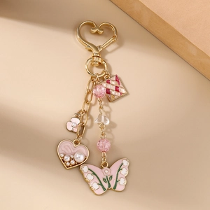 Detail of pink enamel butterfly keychain with heart clasp and pearl charms on gold chain