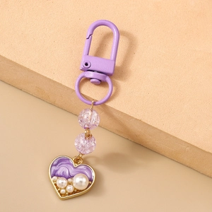 Close-up of purple heart keychain with marble texture and white pearl embellishments